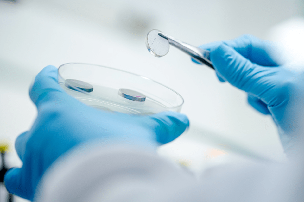 EN 14349 - Microbiologist picking up metal disc from the sterile petri dish for inspection